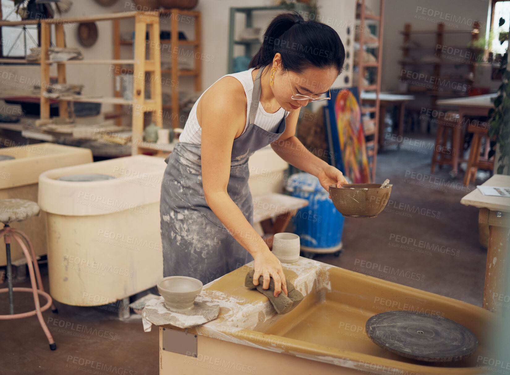 Buy stock photo Pottery, startup business and woman cleaning in workshop for art class, production and manufacturing. Asian artist at creative potter workplace for clay or ceramic school, trade or process with pride