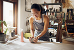 Small business, art and pottery girl entrepreneur in workshop with clay for creativity and inspiration. Creative asian woman working at artistic workspace with happy smile in Tokyo, Japan

