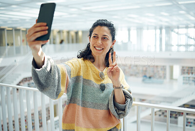 Buy stock photo Selfie, phone and peace with a woman in a library for research while posing for a social media photograph. Mobile, communication and hand gesture with a female student taking a picture in a bookstore