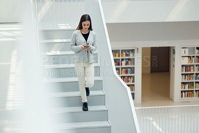 Buy stock photo Phone, social media and research with a woman in the library walking down stairs at university or college. Books, internet and mobile with a female student on a staircase in a bookstore for education