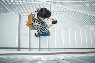 Buy stock photo Phone, stairs and education with a student man walking down a staircase at university or college. Mobile, study and top view with a male pupil taking steps to get to class for learning or development