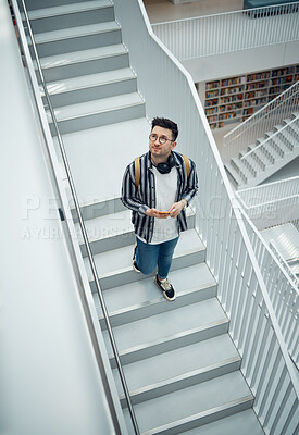 Buy stock photo Library, staircase and student man walking in a education, learning and school research building. College learning, study and bookshelf of person walking down stairs looking at books for information