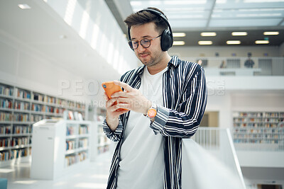 Buy stock photo Phone music, headphones and student in library, university, or college research on mental health, wellness and education. Bookshelf, knowledge and creative, geek man listening to audio on mobile app