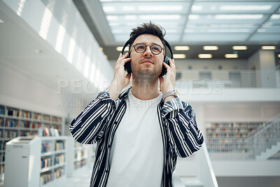 Buy stock photo Student, library and man with music headphones in university, college or school. Thinking, education scholarship and face of young male streaming educational podcast, radio or song, audio or album.