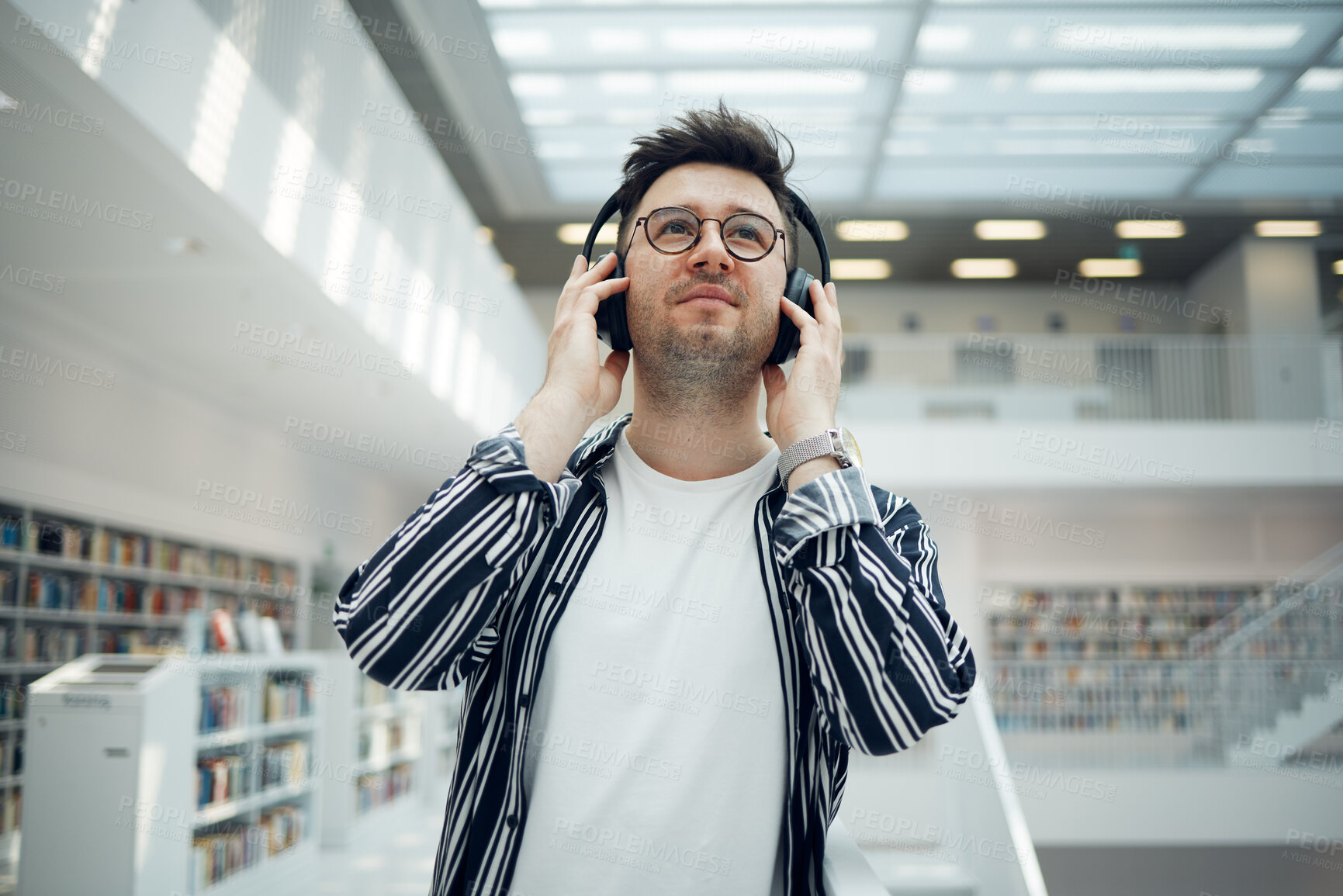 Buy stock photo Student, library and man with music headphones in university, college or school. Thinking, education scholarship and face of young male streaming educational podcast, radio or song, audio or album.