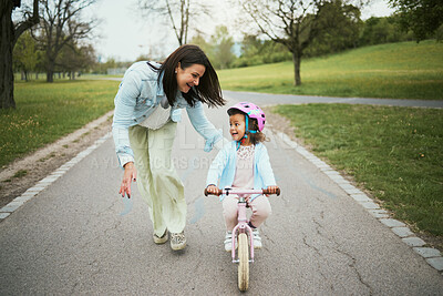 Buy stock photo Children, bike and a mother teaching her girl how to cycle in a park while bonding together as a family. Nature, love and kids with a daughter learning how to ride a bicycle with her mom outside