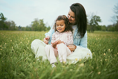 Buy stock photo Children, family and field with a mother and girl sitting on grass together outdoor in nature during summer or spring. Kids, countryside and bonding with a mom and daughter in a green meadow