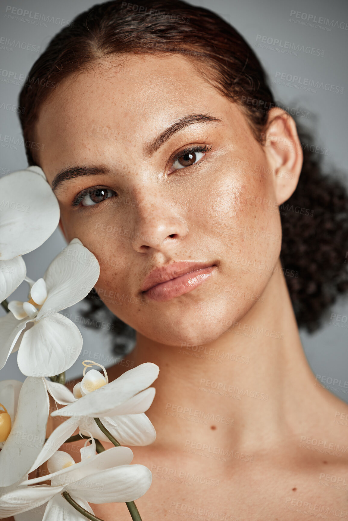 Buy stock photo Face portrait, skincare and woman with orchid in studio isolated on a gray background. Floral makeup, organic cosmetics and female model with flowers for healthy skin treatment, wellness and beauty