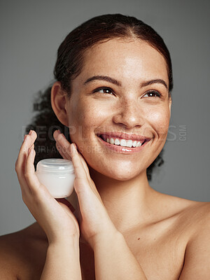 Buy stock photo Wellness, aesthetic and facial cream of black woman  with healthy beauty glow and natural freckles. Thinking skincare girl with smile and luxury face lotion product on gray studio background.

