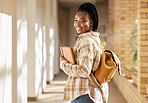 College student, black woman and university with books and backpack while walking down campus corridor. Young gen z female happy about education, learning and future after studying at school building