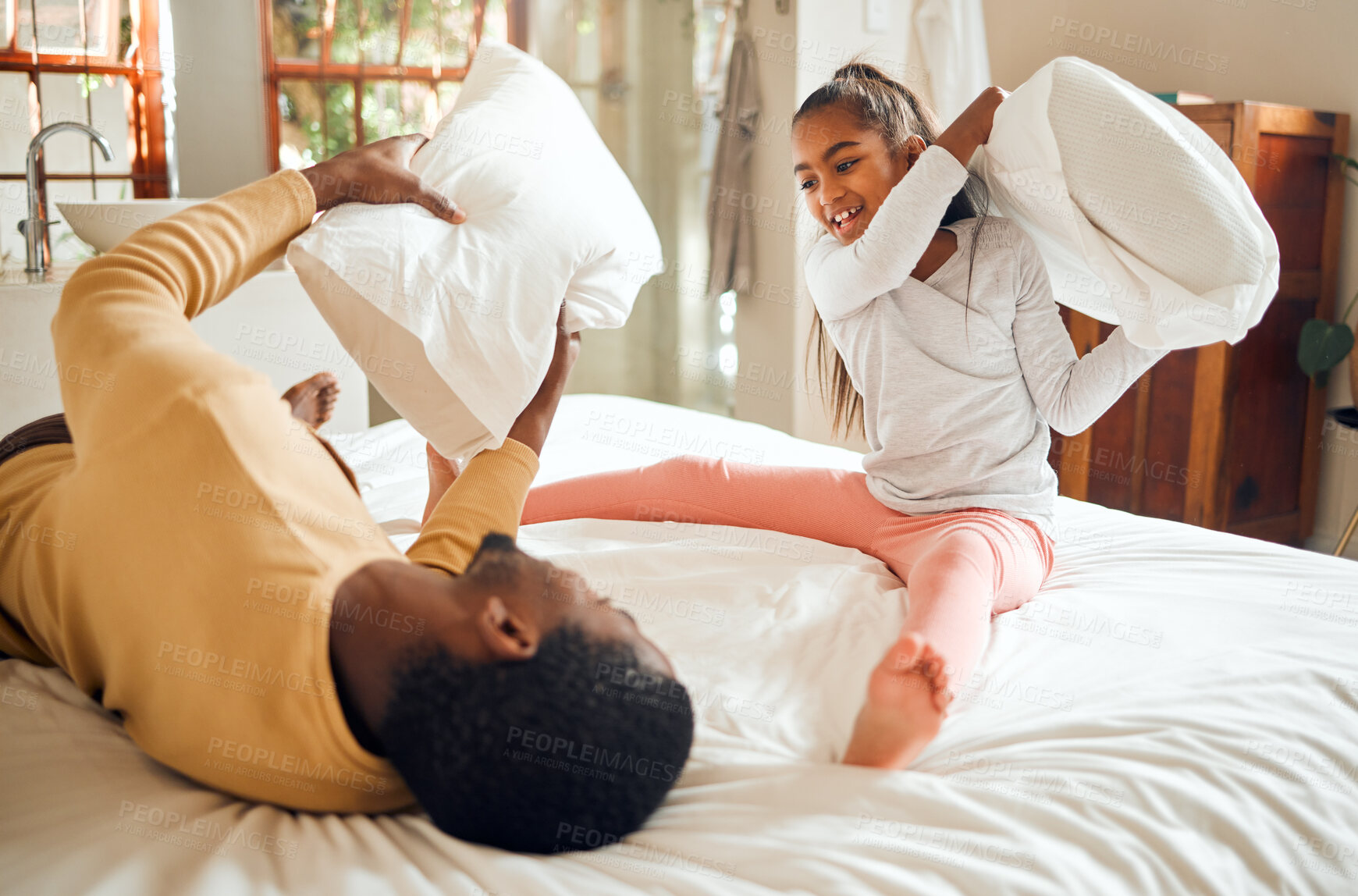 Buy stock photo Happy pillow fight, father and child on bed playing, bonding and crazy fun for dad and daughter time in home. Family, love and playful energy, black man with girl hitting and laughing in bedroom.