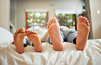 Feet, family and dad sleeping on a bed with child in a bedroom at a home or house bonding together. Resting, break and parent with kid barefoot bonding and relaxing together spending time