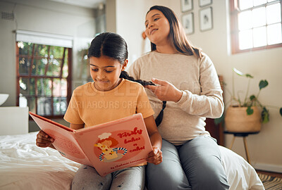 Buy stock photo Family, book or education and a girl reading in a bedroom with her mom playing with her hair in their home. Books, learning and love with a mother and daughter bonding while sitting on a bed together
