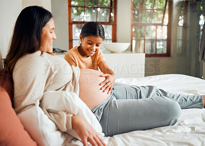 Buy stock photo Pregnant mom and curious child on bed touching belly with excited, happy and joyful smile. Indian family and kid waiting for baby sibling and bonding together with mother in home bedroom.
