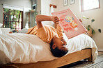 Happy child reading book on bed for home learning, language education and creative development upside down. Smart, intelligent and Indian kid with English story for fun, relax and holiday activity