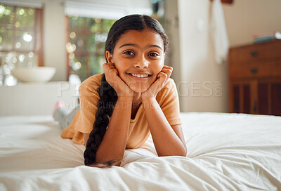 Buy stock photo Girl, happy and portrait of smiling little child looking adorable and lying on bed in a bedroom in a home or house. Young, cute and sweet kid with innocent face relaxing on her hands feeling positive