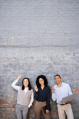 Buy stock photo Business people, peace sign and portrait of friends by a brick wall with a laptop and digital tablet. Happy, smile and corporate team employees standing together with a hand gesture in the urban city