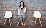Woman waiting for interview on chair with phone, recruitment and employment with smile. Portrait of happy person in Japan sitting on chair, smiling and excited for job opportunity for Japanese people