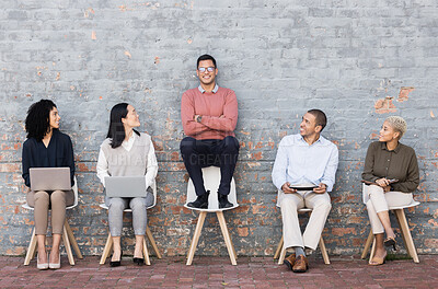 Buy stock photo Creative business people, waiting room and man standing out against a brick wall for interview, meeting or opportunity. Group of employee interns with technology looking at candidate for startup