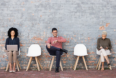 Buy stock photo Business people, waiting room and sitting on chairs against brick wall for interview, meeting or opportunity. Group of creative interns in social distancing, working and checking time for startup