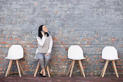Buy stock photo Phone call, queue and woman from Japan on chairs, recruitment and employment with smile at interview. Happy person sitting on chair, wall and smartphone smiling and talking of opportunity for people.