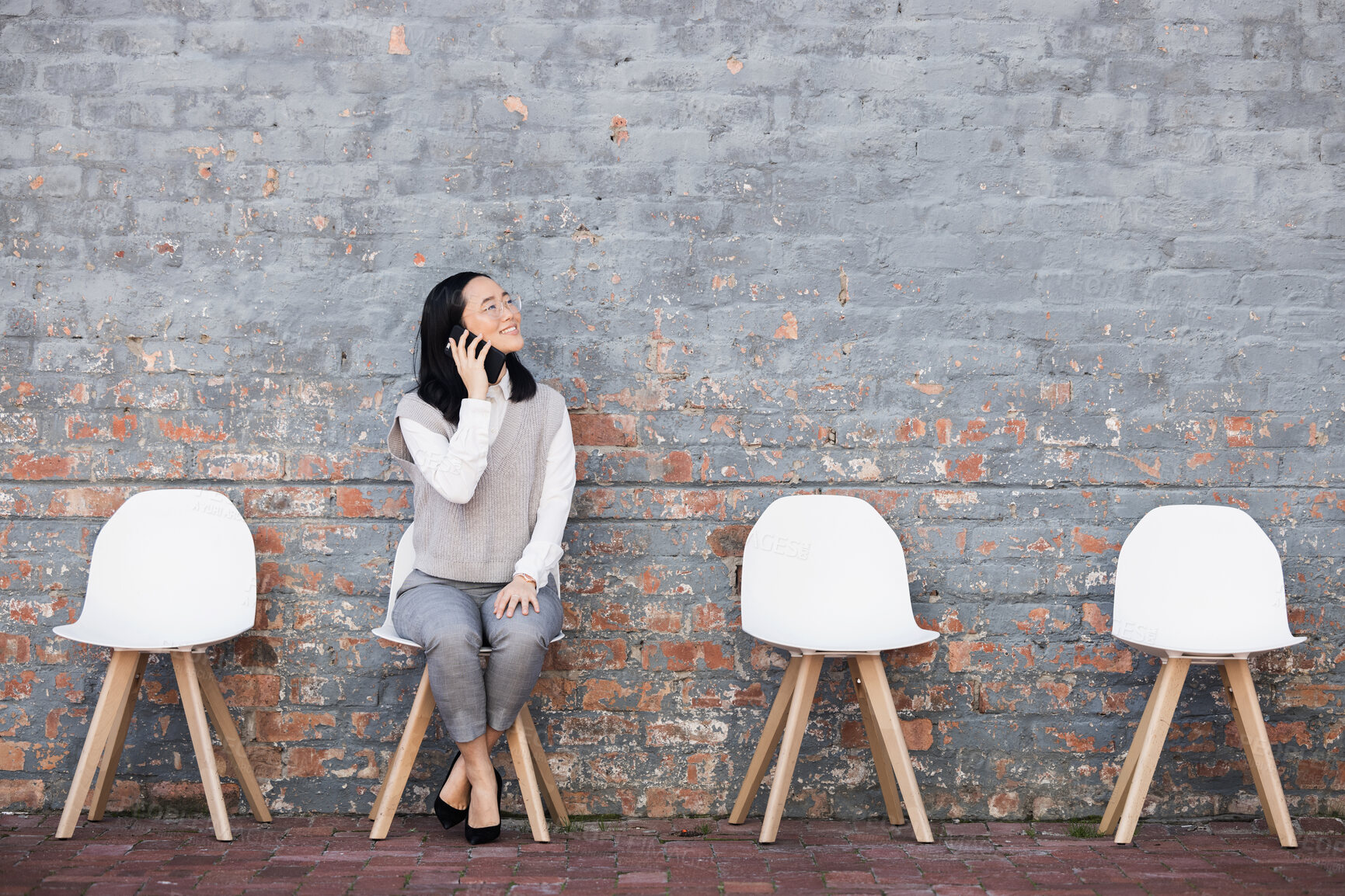 Buy stock photo Phone call, queue and woman from Japan on chairs, recruitment and employment with smile at interview. Happy person sitting on chair, wall and smartphone smiling and talking of opportunity for people.