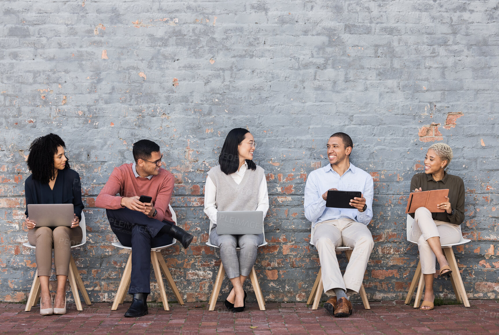 Buy stock photo Employee diversity, interview line and conversation with technology for meeting, recruitment or company hiring. Human resources, happy business people and discussion with laptop, tablet or smartphone