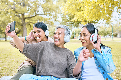 Buy stock photo Headphones, friends phone selfie and women at park taking pictures for social media. Mobile, retirement and group of senior females streaming music, taking photo and laughing at comic meme or joke.
