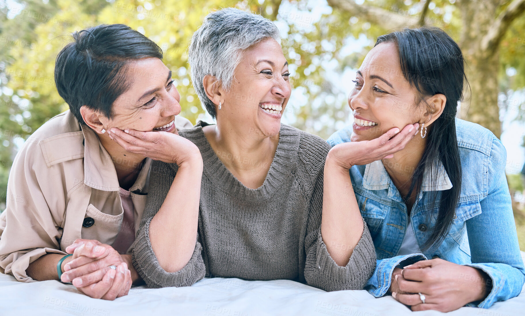 Buy stock photo Love, senior women and friends at park on picnic blanket, bonding and enjoying quality time together outdoors. Peace, retirement and happy group of elderly females embrace and relaxing in nature.