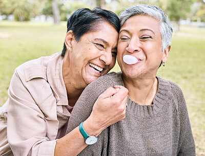 Buy stock photo Senior women, friends and hug in park for comic, funny and happy time together in nature with bubblegum. Old woman, embrace and laughing for memory, joke or bubble by trees, nature or forest to relax