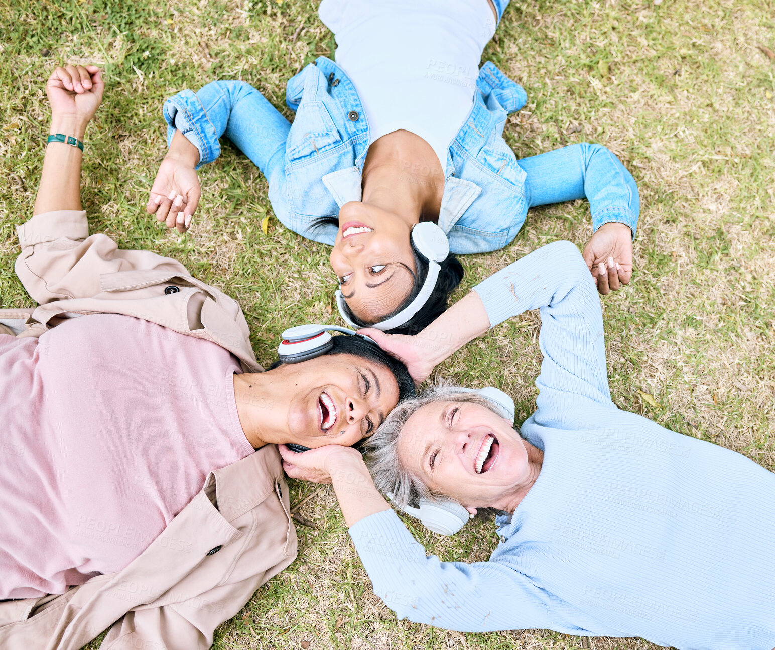 Buy stock photo Top view, senior or people and music headphones in silent disco, retirement friends fun or bonding community wellness. Smile, happy or elderly women lying on nature park grass and listening to radio
