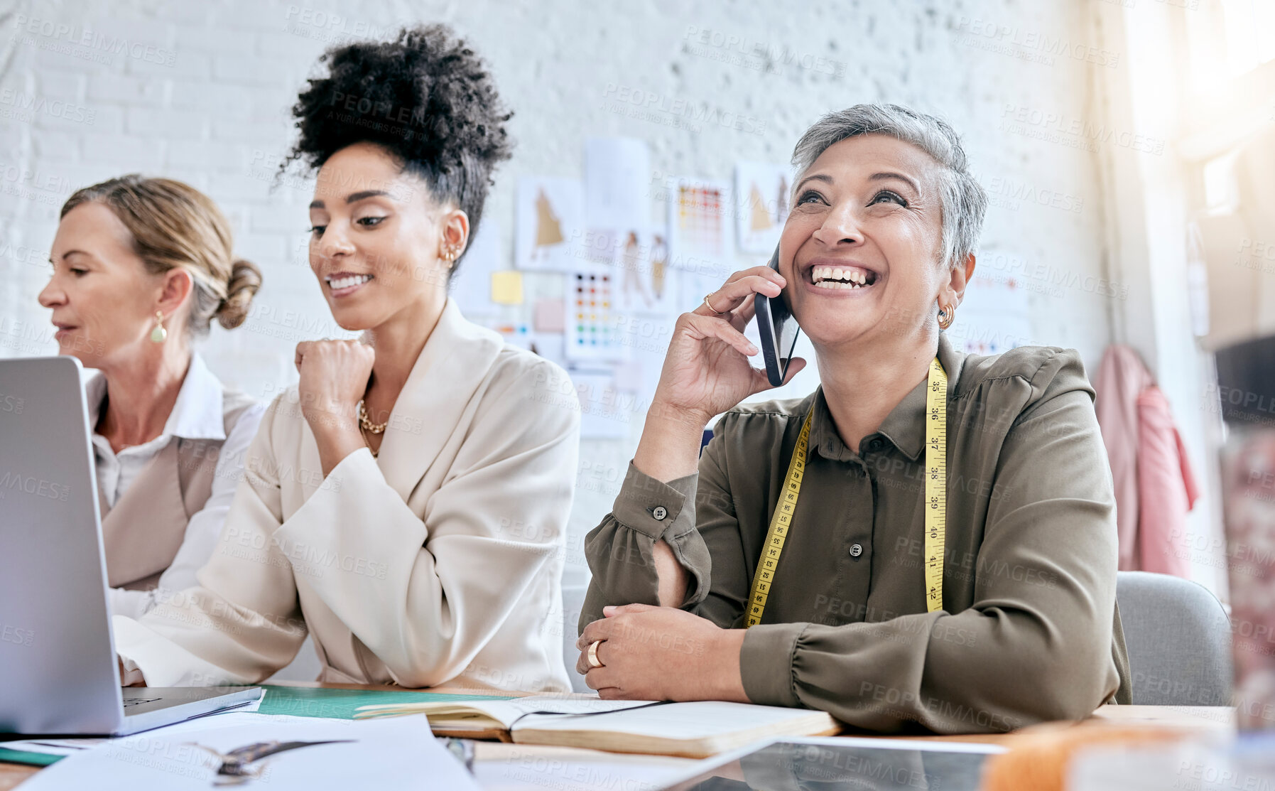 Buy stock photo Designer, fashion and senior woman on phone call with contact in workshop. Group collaboration, small business and teamwork of female tailors in boutique with laptop planning, talking and discussing.