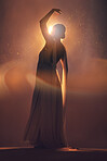 Fantasy, orange lighting and silhouette of woman with stylish dress for creative fashion, art deco and beauty. Dance, aesthetic and shadow of girl pose for dream, magic and freedom in glowing studio