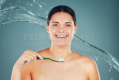 Happy, grooming and portrait of a woman brushing teeth isolated on a blue background. Water splash, health and face of a clean, smiling and young model taking care of dental hygiene with toothpaste