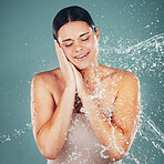 Water, splash and cleaning with a woman in studio on a blue background for hygiene or hydration in the shower. Spa, wellness and beauty with an attractive young female washing in the bathroom