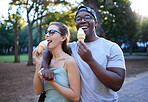 Love, ice cream or couple of friends in a park walking on a romantic date in nature in an interracial relationship. Romance, black man and happy woman eating or enjoying a snack on a holiday vacation