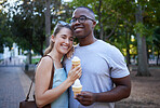 Happy, interracial and couple eating ice cream in a park on a date, anniversary or walk together. Love, smile and man and woman with a sweet dessert while walking in nature with romantic affection