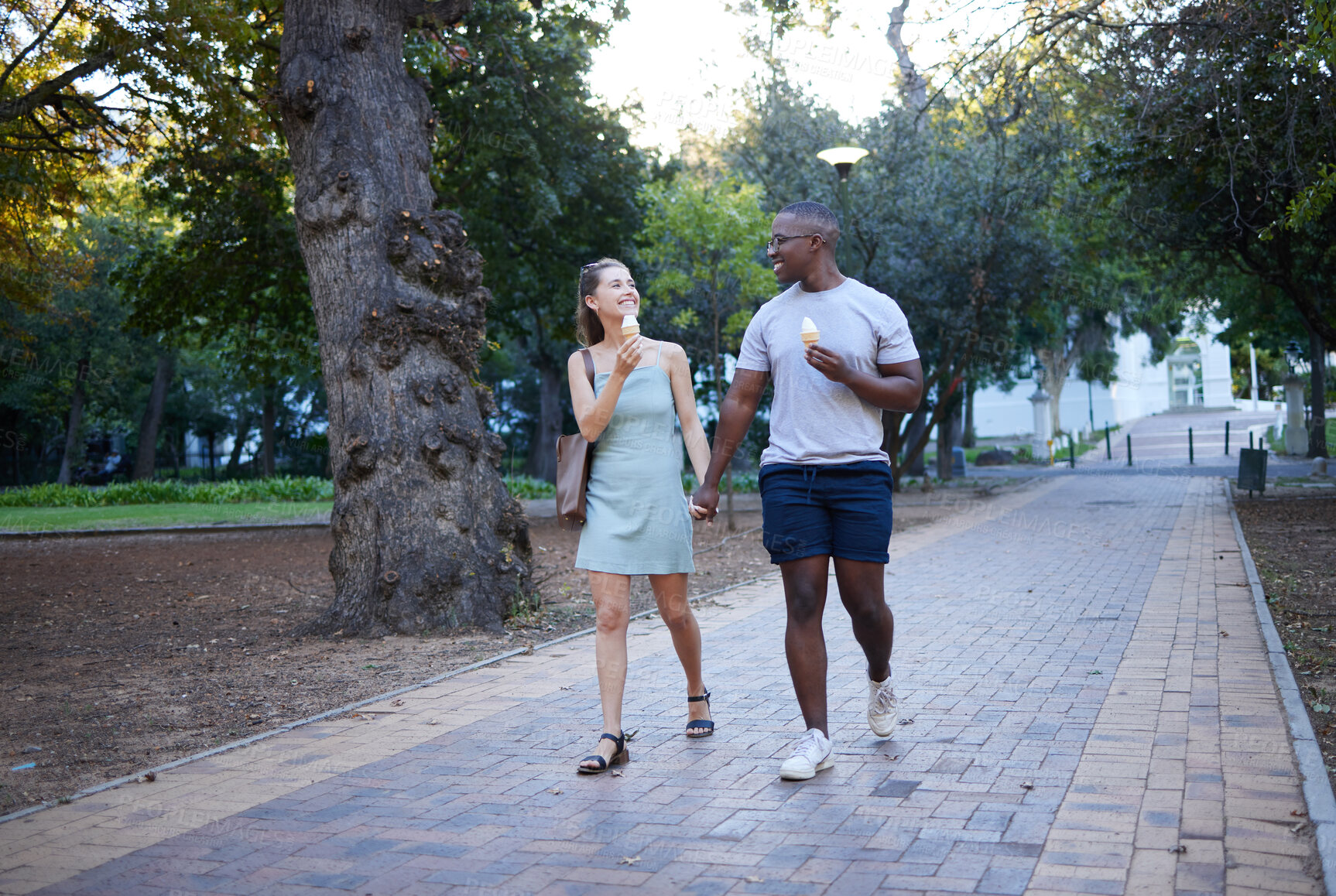 Buy stock photo Couple on date in park, ice cream and holding hands outdoor, love and commitment in relationship. Romance in nature, black man and woman eat dessert for quality time together, trust and interracial