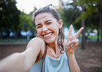 Selfie, peace and face with a woman in a park, posing for a photograph alone outdoor in nature. Social media, emoji and hand sign with an attractive young female alone outside in a garden or field