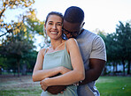 Happy interracial couple, hug and smile for love, care or bonding together in the nature park. Woman smiling with man hugging her for relationship embrace, support or trust kissing shoulder outside