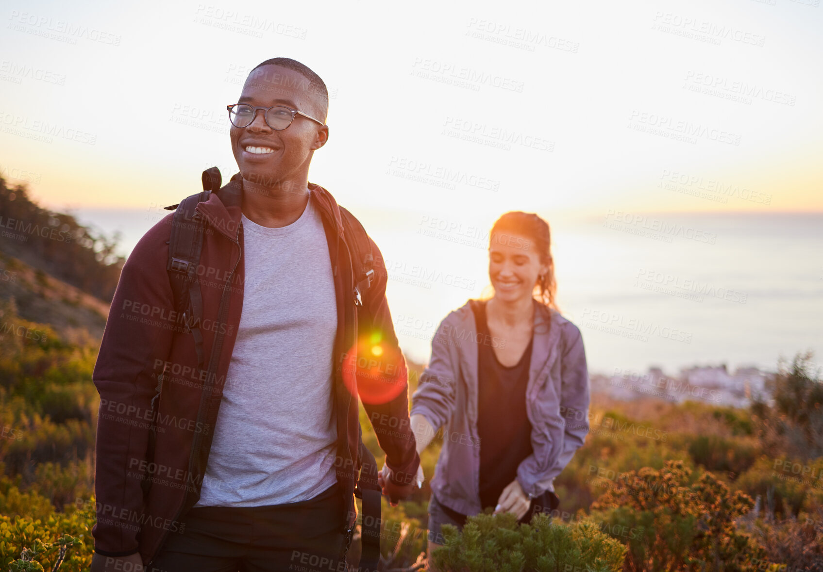 Buy stock photo Interracial couple, workout and hiking exercise in sunset on a mountain as morning fitness in nature. Happy people, man and woman in a relationship training for health and wellness together