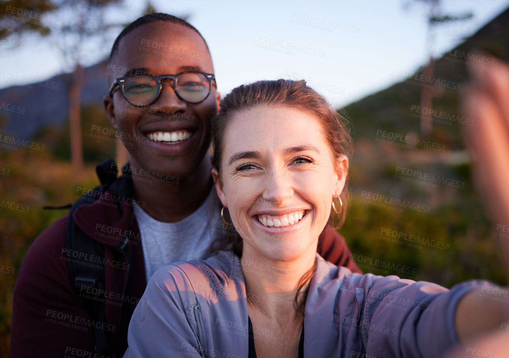 Buy stock photo Nature, selfie and portrait of interracial couple on mountain for holiday, vacation and hiking adventure on weekend. Travel, wellness and happy man with woman enjoy calm, freedom and peace at sunset