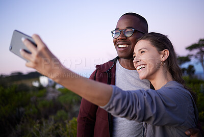 Buy stock photo Interracial couple, phone and smile for selfie, journey or travel adventure or trip together in the nature outdoors. Happy woman holding smartphone with man for photo or social media at a safari