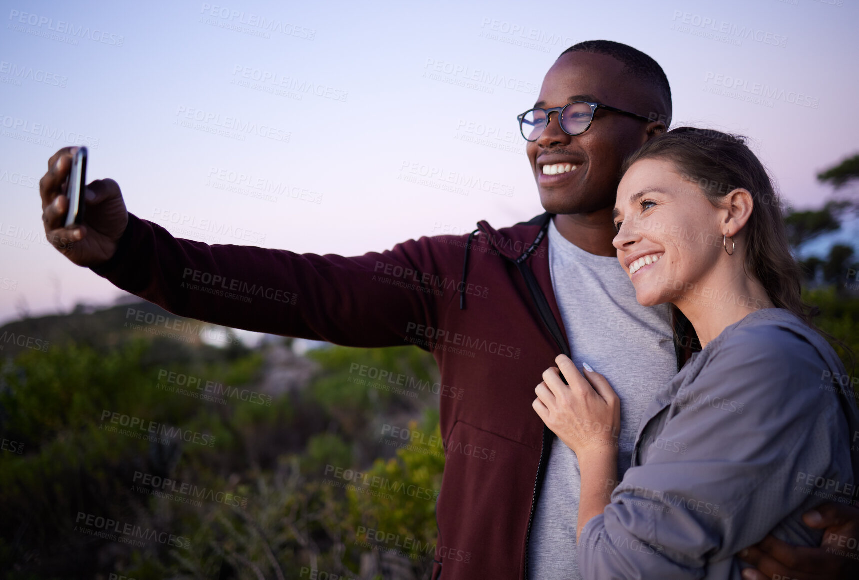 Buy stock photo Interracial couple, phone and smile for selfie, travel or adventure trip together in the nature outdoors. Happy man holding smartphone and taking a photo with woman smiling in happiness for journey