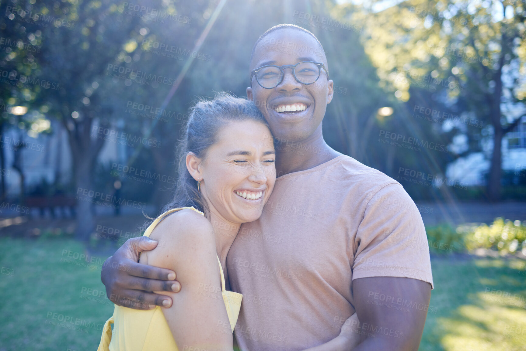 Buy stock photo Happy interracial couple, hug and laughing in joy for bonding relationship together in the park. Man hugging woman smiling in happiness for love, embrace and sharing a laugh for funny joke in nature