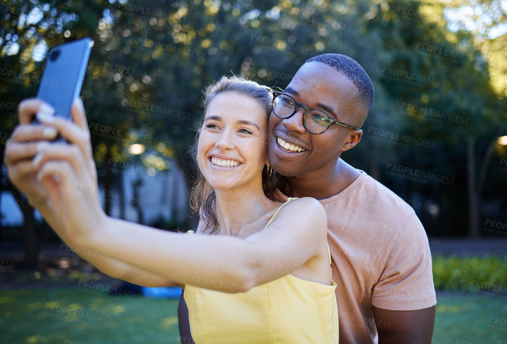 Buy stock photo Selfie, phone and interracial couple smile in park enjoying weekend, summer holiday and quality time together. Nature, dating and happy man and woman relax, calm and hug to take picture on smartphone