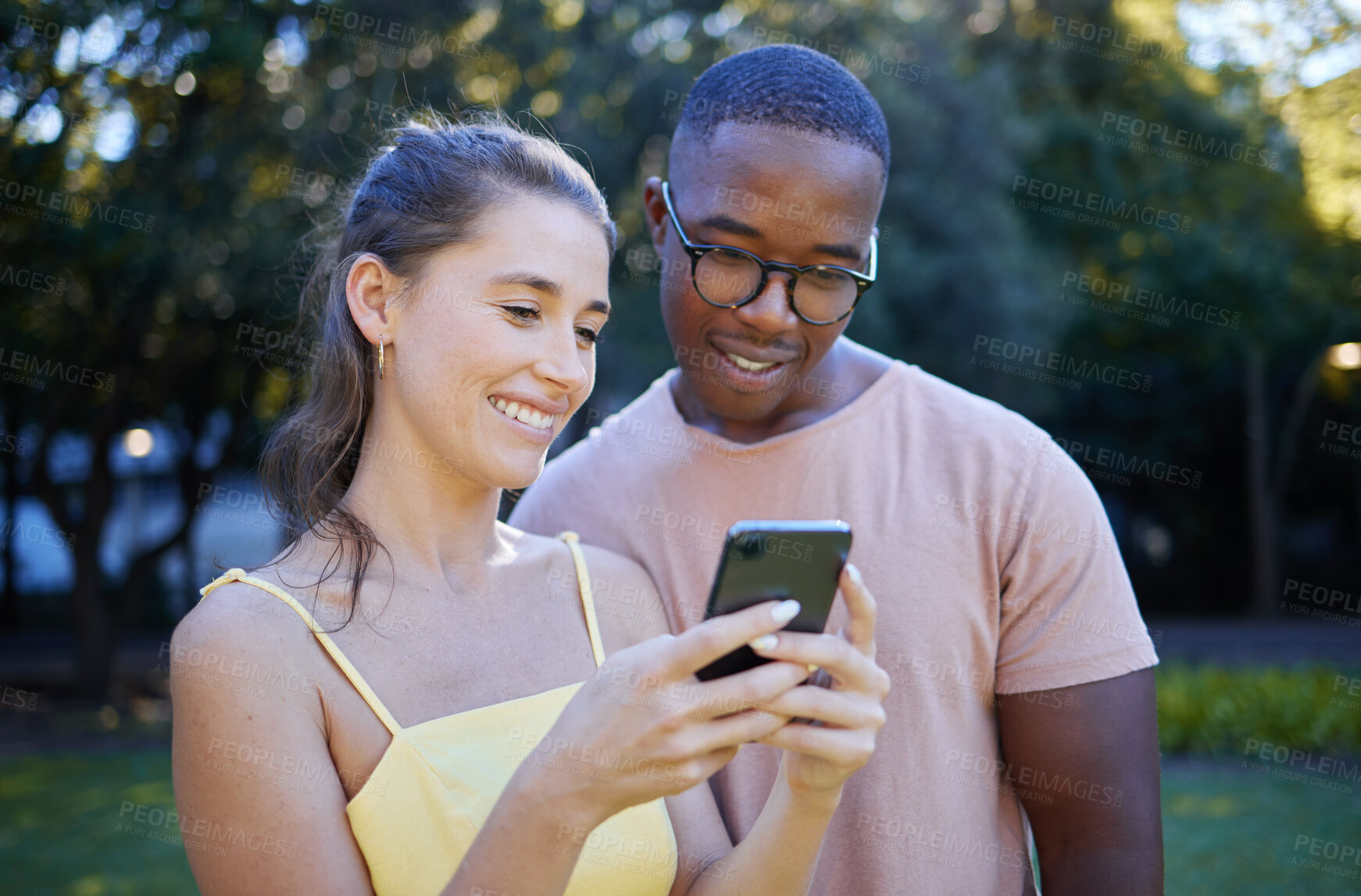 Buy stock photo Interracial, meme and couple with a phone in a park, funny communication and laughing at social media. Comic, streaming and black man and woman reading a joke on a mobile in nature of France