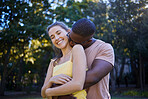 Couple in portrait, date in park with hug and outdoor in nature, love and commitment with interracial relationship. Trust, support and happy people, black man and woman smile on face with fresh air