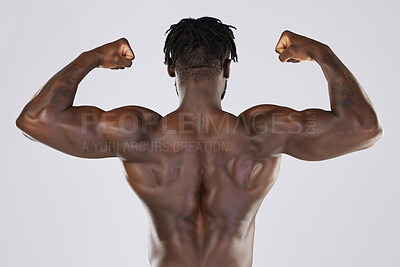 Buy stock photo Flexing, muscle and back of a black man with power isolated on a grey studio background. Fitness, sexy and strong body of an African bodybuilder showing biceps from gym exercise on a backdrop