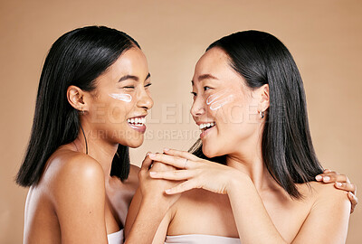 Buy stock photo Laughing, beauty and excited women with cream for face isolated on beige studio background. Wellness, smile and Asian model friends with sunscreen for love of cosmetics and dermatology on a backdrop